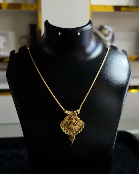 Gold kanthi with a pointed pendant, on a display bust